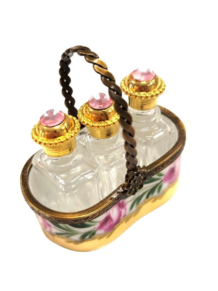 Vintage Limoges luxury French perfume bottles set with gold accents and pink gem stoppers in decorative holder