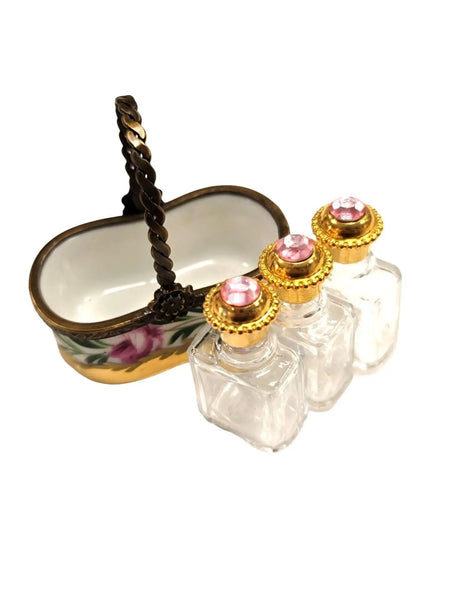 Vintage Limoges luxury French perfume bottles with gold accents and pink gem tops beside decorative ceramic basket